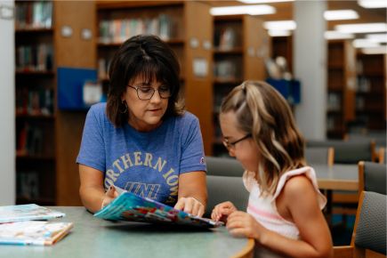 Librarian working with children and helping with reading
